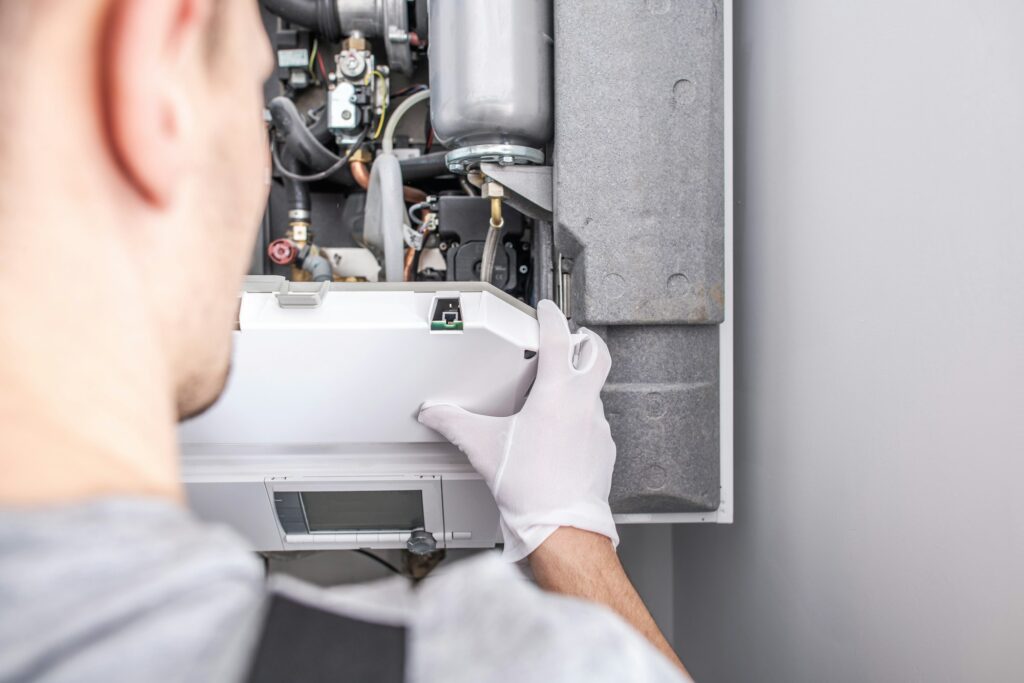 Technician repairing a central heating furnace system, emphasizing HVAC maintenance for homeowners considering furnace replacement.