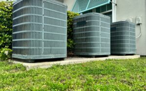 Three outdoor air conditioning units beside a residential building, showcasing HVAC systems relevant to spring maintenance and repair in Noblesville, IN.