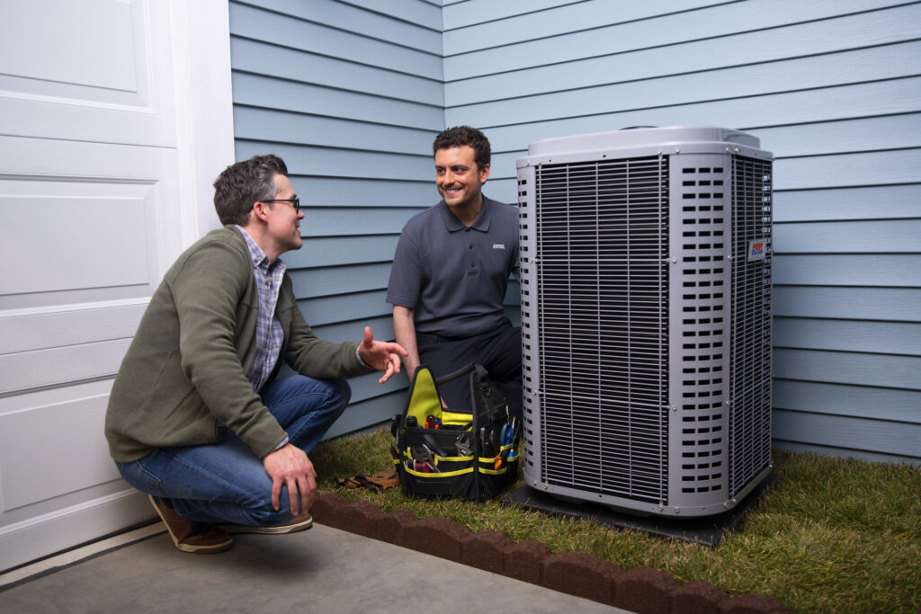 Man discussing air conditioning repair with technician beside outdoor AC unit, showcasing professional service and customer interaction.