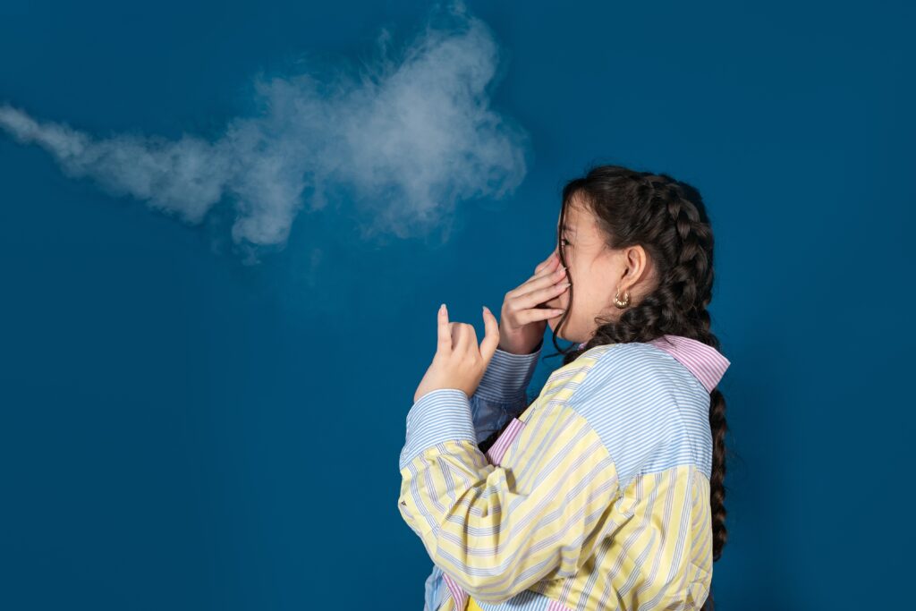 Teen girl pinching her nose and reacting to unpleasant smell, illustrating air quality concerns related to HVAC issues.